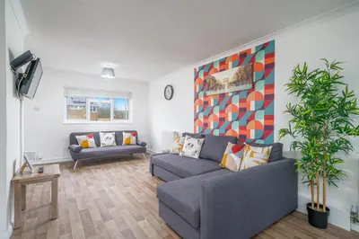 a living room with a couch and a plant at Skyvillion-STEVENAGE Amazing 3Bed House, Garden, Free Off Street Parking for 2 Cars, WiFi in Stevenage