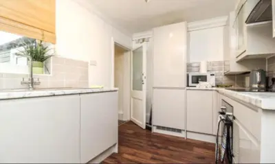 a white kitchen with white cabinets and a counter top at Charming Victoria Conversion Flat in Brentwood with a Garden & Free Parking in Brentwood