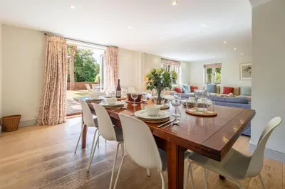 a dining room and living room with a wooden table and chairs at Alexander House in Thorpeness