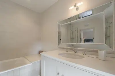 a white bathroom with a sink and a mirror at Alexander House in Thorpeness