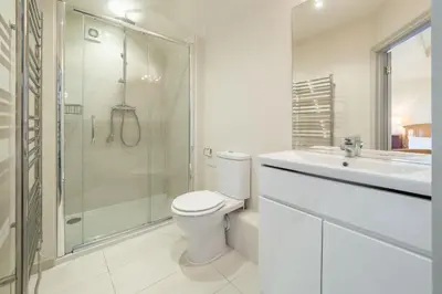 a white bathroom with a toilet and a shower at Alexander House in Thorpeness