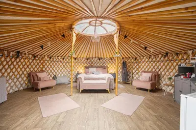 a bedroom in a yurt with a bed and two chairs at Glamp and Tipple Ltd in Great Ellingham