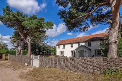 a white house behind a stone fence at Alexander House 4 in Thorpeness