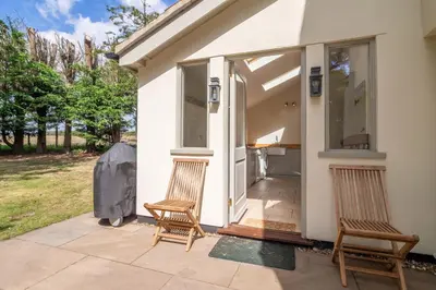 two chairs sitting on a patio next to a house at Alexander House 4 in Thorpeness