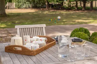 a picnic table with a basket of dishes and a glass at Alexander House 6 in Thorpeness