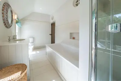 a white bathroom with a tub and a sink at Alexander House 6 in Thorpeness