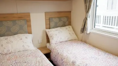 a bedroom with two beds and a window at Excellent caravan 2 bedrooms sleeps 6 in East Mersea