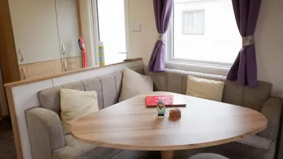 a table and a couch with a book on it at Excellent caravan 2 bedrooms sleeps 6 in East Mersea