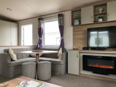 a living room with a fireplace and a tv at Excellent caravan 2 bedrooms sleeps 6 in East Mersea
