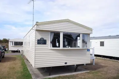 a small white trailer with a sign on it at Excellent caravan 2 bedrooms sleeps 6 in East Mersea