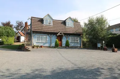 a blue house with a brown roof and a driveway at Flink's Barn in Great Dunmow