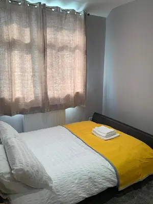 a bed with a yellow blanket and a window at Breeze on Southend in Essex in Southend-on-Sea