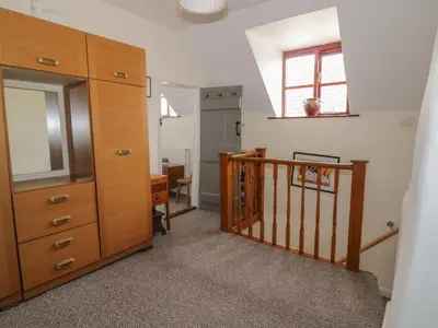 a room with a staircase and a dresser with a mirror at Rose Cottage in Ipswich