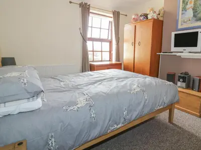 a bedroom with a bed with a blue blanket at Rose Cottage in Ipswich