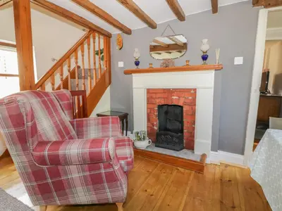 a living room with a fireplace and a chair at Rose Cottage in Ipswich
