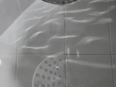 a shower stall with a shower head and a drain at Chequer Cottage in Horseheath
