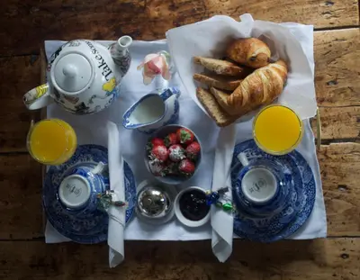 a table with a breakfast of croissants bread and orange juice at Chequer Cottage in Horseheath