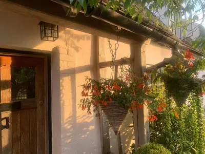 a basket of flowers hanging from the side of a house at Chequer Cottage in Horseheath