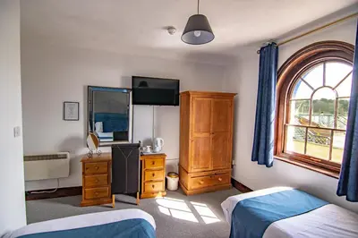 a bedroom with two beds and a dresser and a window at The Station Guest House in Woodbridge