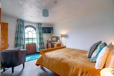 a bedroom with a bed and a chair and a window at The Station Guest House in Woodbridge