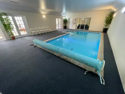 a large swimming pool in a large room with a blue swimming pool at Aldercarr Hall in Attleborough