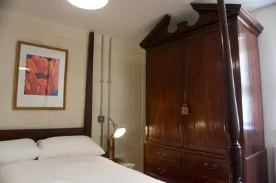 a bedroom with a bed and a wooden cabinet at Stunning Apartment with Courtyard Near The Waterfront Ipswich in Ipswich