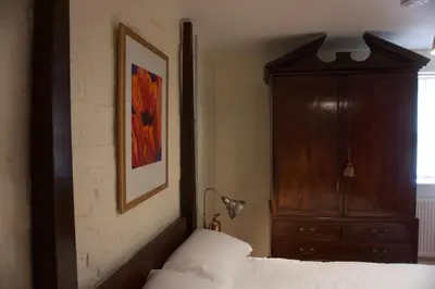 a bedroom with a bed and a wooden cabinet at Stunning Apartment with Courtyard Near The Waterfront Ipswich in Ipswich