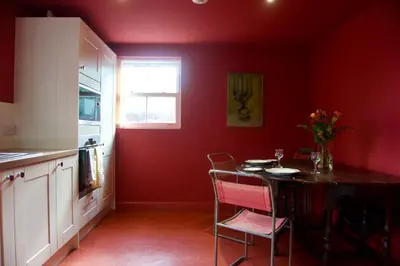 a kitchen with red walls and a table and chairs at Stunning Apartment with Courtyard Near The Waterfront Ipswich in Ipswich