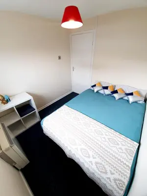 a small room with a bed and a red lamp at Rayleigh Town Centre 3 Bedroom Apartment in Rayleigh