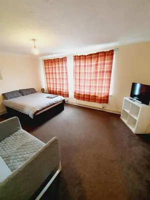 a bedroom with two beds and a tv and two windows at 4 Bedroom Thundersley Apartment in Rayleigh