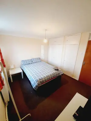 a bedroom with a bed with a plaid blanket at 4 Bedroom Thundersley Apartment in Rayleigh