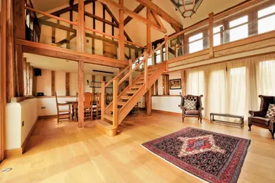 a large living room with a staircase in a house at Old Oak Barn - Beautiful barn conversion with wonderful Jacuzzi hot tub in Stowmarket