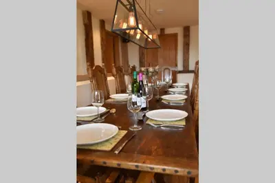 a long wooden table with white plates and wine glasses at Old Oak Barn - Beautiful barn conversion with wonderful Jacuzzi hot tub in Stowmarket