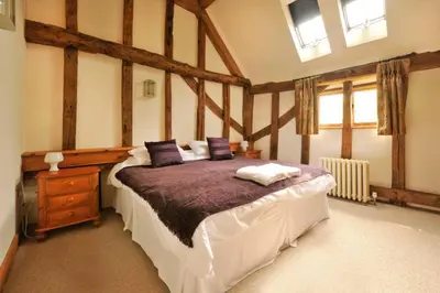 a bedroom with a large bed with purple pillows at Old Oak Barn - Beautiful barn conversion with wonderful Jacuzzi hot tub in Stowmarket