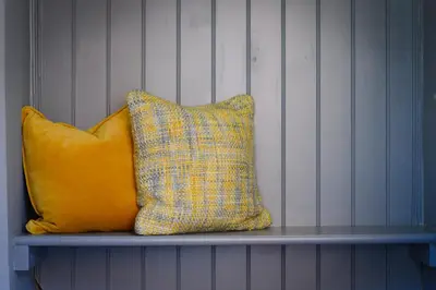 two pillows sitting on a bench against a wall at The Gate Cottage in Thaxted