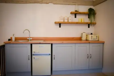 a kitchen with a counter with a sink and a refrigerator at The Gate Cottage in Thaxted