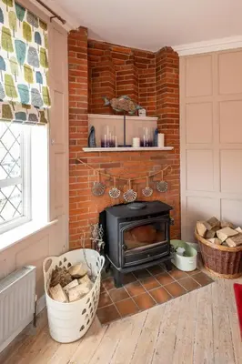 a brick fireplace in a living room with a stove at 1 Westgate in Thorpeness