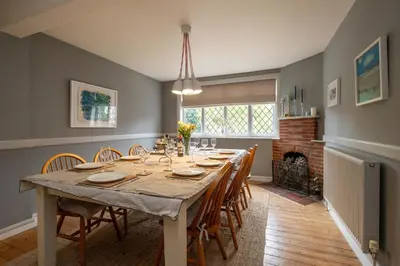 a dining room with a table with chairs and a fireplace at 1 Westgate in Thorpeness