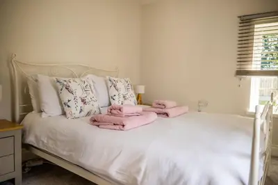 a bedroom with a bed with pink towels on it at The Stables in Halesworth