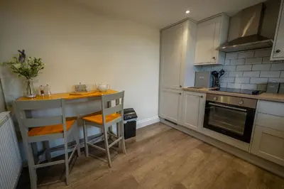 a kitchen with white cabinets and a table in it at The Stables in Halesworth
