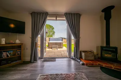 a living room with a door open to a patio at The Stables in Halesworth