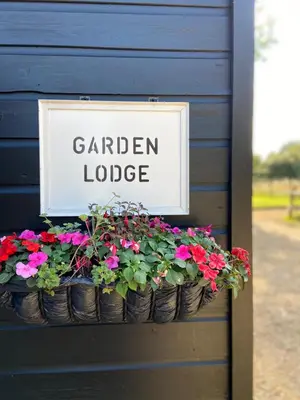 a sign on a blue house with flowers in buckets at Spacious Garden Lodge at The Chestnuts, Norfolk in Norwich