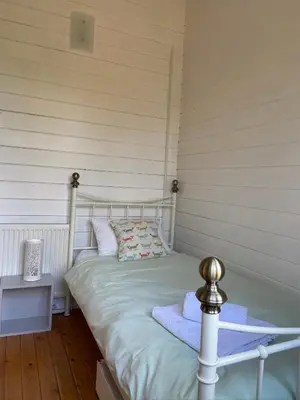 a bed in a room with a white wall at Spacious Garden Lodge at The Chestnuts, Norfolk in Norwich