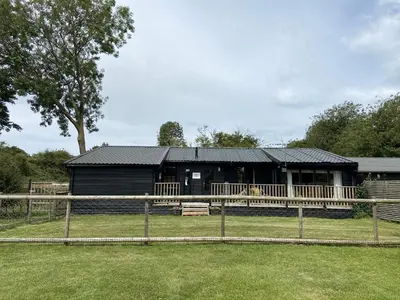 a black house with a fence in front of it at Spacious Garden Lodge at The Chestnuts, Norfolk in Norwich