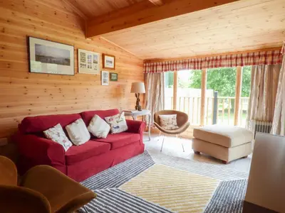 a living room with a red couch in a cabin at Spacious Garden Lodge at The Chestnuts, Norfolk in Norwich