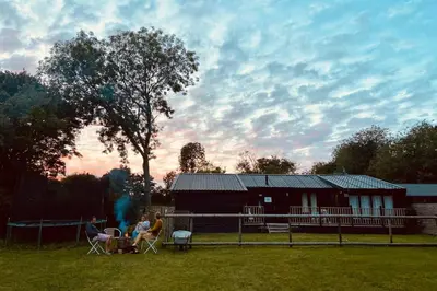 a group of people sitting in chairs in front of a house at Spacious Garden Lodge at The Chestnuts, Norfolk in Norwich