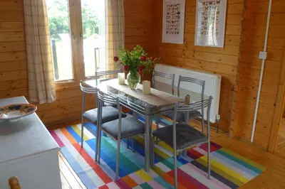 a kitchen with a table and chairs on a colorful rug at Spacious Garden Lodge at The Chestnuts, Norfolk in Norwich