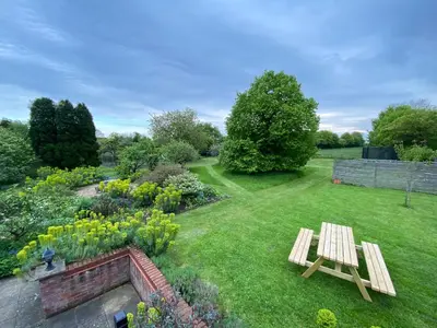 a garden with a wooden bench in the grass at Spacious Garden Lodge at The Chestnuts, Norfolk in Norwich
