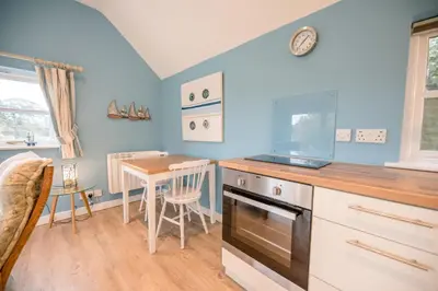 a kitchen with a table and a stove top oven at Little House, Aldringham in Leiston