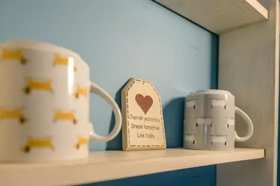 two mugs and a cup on a shelf at Little House, Aldringham in Leiston